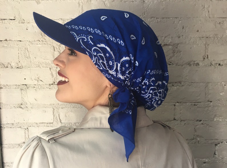 May include: A royal blue bandana with a white paisley pattern is tied around a person's head and styled into a cap with a visor.