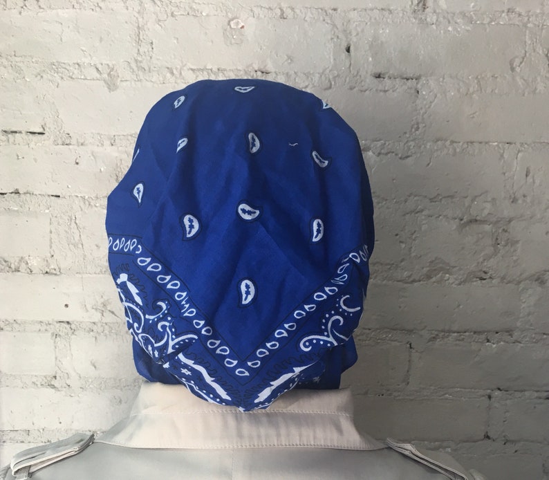 May include: A blue bandana with a white paisley pattern. The bandana is folded and tied on a person's head.