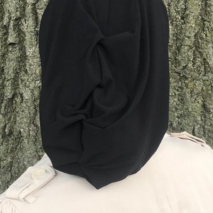 K&ouml;nnte beinhalten: Ein schwarzes Kopftuch mit einem Knotendesign. Das Tuch ist aus einem weichen, glatten Stoff.