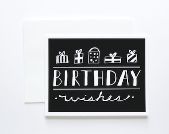 May include: Black and white birthday card with the text "BIRTHDAY wishes." and a row of five white gift boxes with black details.
