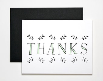 May include: A white card with black and green lettering that says "THANKS". The lettering is surrounded by small black and green leaf designs.