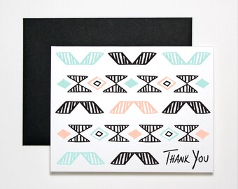 May include: A white thank you card with a geometric pattern in black, light blue, and peach. The pattern is made up of triangles, diamonds, and lines. The text "THANK YOU" is written in black at the bottom of the card.