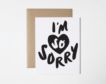 May include: A white card with black text that reads "I'm so sorry" with a black heart in the middle that says "so" in white text.