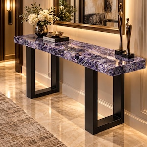 May include: A rectangular console table featuring a polished purple amethyst gemstone slab top with a natural crystalline texture. The table is supported by two sturdy black metal U-shaped legs and stands as a prominent piece of furniture.