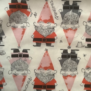 May include: White fabric with a repeating pattern of cartoon gnomes. The gnomes have red and gray outfits, pink cone-shaped hats, and long white beards. The word "GNOMES" is printed on the fabric. Small flowers and insects are also scattered across the fabric.