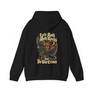 May include: A black hooded sweatshirt featuring a graphic on the back of a raccoon wearing a wizard hat and cape, riding a large raven. The text reads Let's Roll Math Rocks And Do War Crimes, surrounded by stars and a crescent moon.