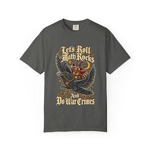 May include: A charcoal gray t-shirt featuring a graphic of a raccoon wearing a wizard hat and cape, riding a large black raven. The text reads Let's Roll Math Rocks And Do War Crimes, accompanied by a crescent moon and small stars.