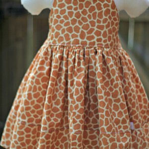 K&ouml;nnte beinhalten: Ein &auml;rmelloses Kleid mit Giraffenmuster. Das Kleid hat einen gerafften Rock und ist aus einem weichen, leichten Stoff gefertigt. Das Kleid ist perfekt f&uuml;r einen Sommertag.