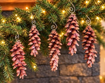 May include: Five hanging ornaments shaped like pinecones, each painted in a metallic reddish-copper hue with subtle glitter accents. Every ornament features a gold-toned metal wire hook with a decorative spiral loop at the top for hanging.
