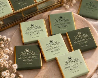 Puede incluir: Tabletas de chocolate cuadradas envueltas en papel verde salvia claro y oscuro con bordes de papel de aluminio dorado. Cada barra presenta una ilustración floral, los nombres AISHA & MICHAEL y la fecha 12. 12. 2023 en negro.