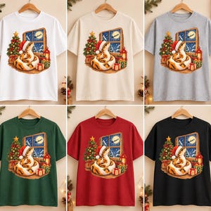 May include: A collection of six short-sleeve t-shirts in white, beige, gray, dark green, red, and black. Each shirt features a graphic of a snake wearing a Santa hat, sitting near a Christmas tree, gifts, and a window showing a moonlit night.
