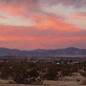 Pode incluir: Uma pintura de paisagem de um deserto ao pôr do sol com um céu vibrante em tons de rosa e laranja sobre cadeias de montanhas escuras. O primeiro plano mostra arbustos baixos e vegetação esparsa em um terreno arenoso e seco.