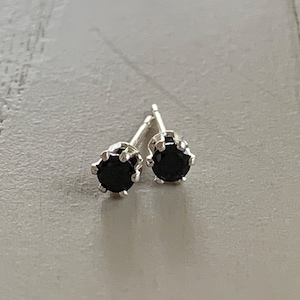 May include: A pair of silver stud earrings with black gemstones.