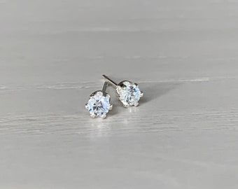 May include: A pair of silver stud earrings with clear round cubic zirconia stones.
