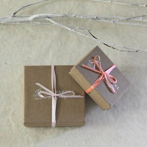 May include: Two small brown gift boxes with pink ribbon bows. The boxes are tied with ribbon and have a white label with the text "The Barefoot Gypsy Jewelry Shop" printed on them.