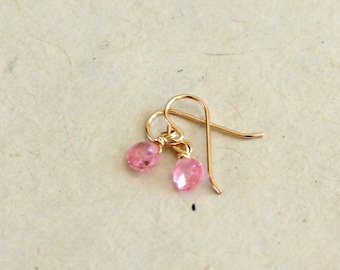 May include: A pair of delicate gold earrings with pink gemstone drops.