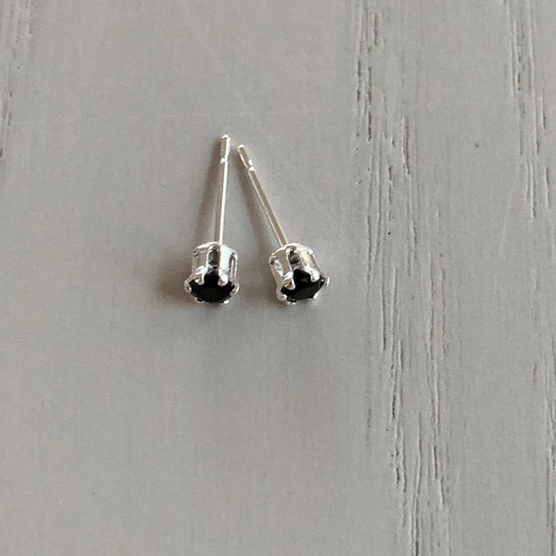 May include: A pair of silver stud earrings with small black gemstones.