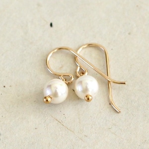 May include: A pair of gold earrings with small white pearl drops.