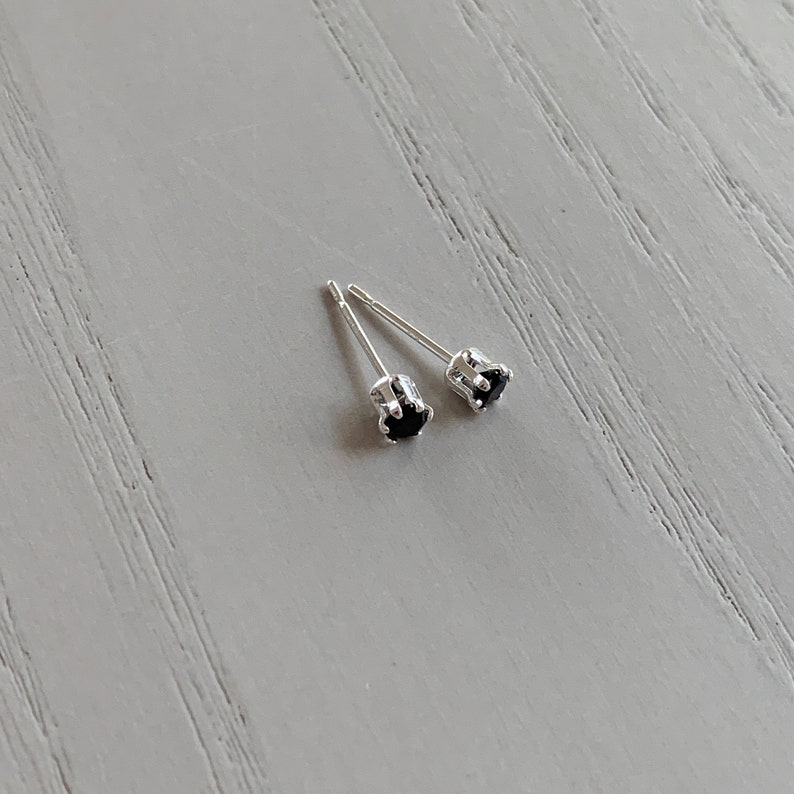 May include: A pair of silver stud earrings with small black gemstones.