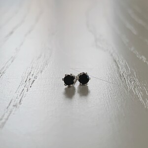 May include: A pair of silver stud earrings with black round gemstones.
