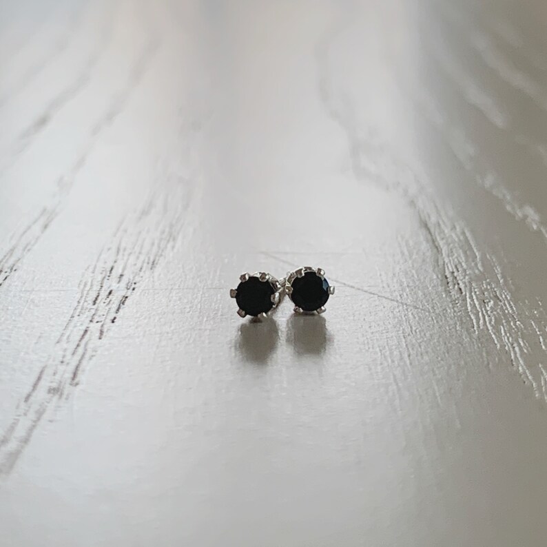 May include: A pair of silver stud earrings with black round gemstones.