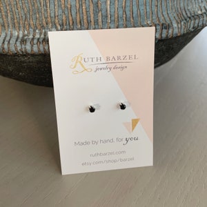 May include: A pair of black stud earrings on a white card with the text "Ruth Barzel jewelry design" and "Made by hand, for you. ruthbarzel.com etsy.com/shop/barzel"