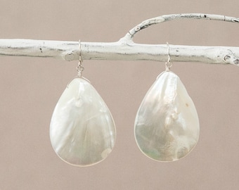 May include: A pair of white teardrop-shaped earrings made from mother of pearl with silver hooks.