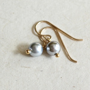May include: A pair of silver pearl earrings with gold hooks.