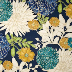 Pode incluir: Um padrão floral repetido com grandes flores estilizadas. As cores incluem branco, verde-azulado e dourado sobre um fundo azul marinho escuro. O design apresenta pétalas e folhas detalhadas, criando uma textura. O tema é botânico.