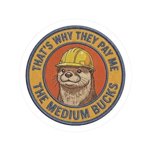 May include: A circular embroidered patch featuring an illustration of an otter wearing a yellow hard hat. The background is orange, surrounded by a gold border with the blue text THAT'S WHY THEY PAY ME THE MEDIUM BUCKS.