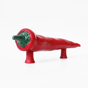 May include: A red chili pepper shaped door handle with a green top and two small legs.