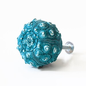 May include: Teal blue sea urchin shaped cabinet knob with a silver metal screw.