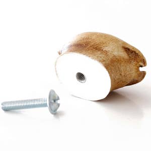 Może przedstawiać: Brązowa ceramiczna gałka drzwiowa z białym otworem na śrubę i srebrną śrubą. Śruba jest oddzielona od gałki.