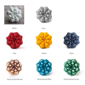 May include: A collection of eight star-shaped decorative knobs in various colours including white, grey, red, yellow, black, hand-painted brown, hand-painted blue, and hand-painted green. Each knob features a textured, geometric, multi-faceted surface.
