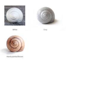 Pode incluir: Tr&ecirc;s esculturas de conchas de caracol em diferentes cores: branco, cinza e marrom pintado &agrave; m&atilde;o.