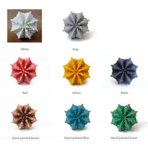 Pode incluir: Oito ornamentos em forma de estrela em v&aacute;rias cores, incluindo branco, cinza, vermelho, amarelo, preto, marrom, azul e verde. Os ornamentos s&atilde;o feitos de um material texturizado e t&ecirc;m um design geom&eacute;trico &uacute;nico.