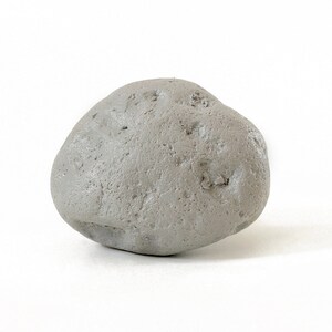 May include: A smooth, gray, rounded stone with a slightly irregular shape.