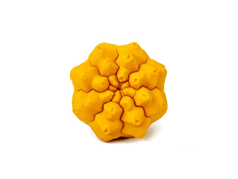May include: A bright yellow, multi-faceted geometric object with a complex, repeating star-like pattern. The surface features numerous small, raised protrusions and deep, intersecting grooves that radiate from the center outward.