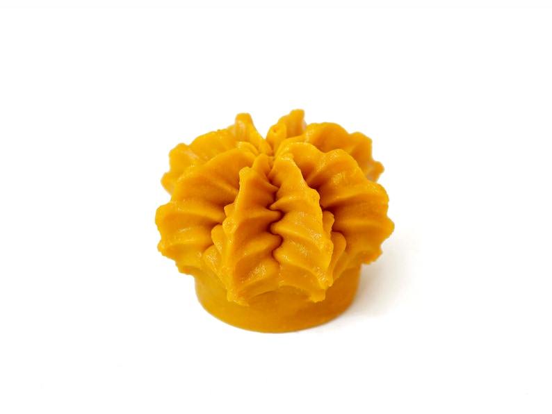 May include: A yellow, flower-shaped candle with a textured surface.