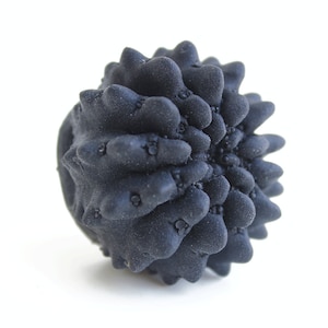 May include: A black, spiky, round object resembling a sea urchin. The object is made of a textured material and has a rough surface.
