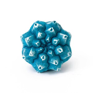 May include: A bright blue, star-shaped object with a textured, multi-faceted surface. The points of the star feature white, weathered-looking highlights, creating a contrast against the deep blue base colour of the geometric, symmetrical form.