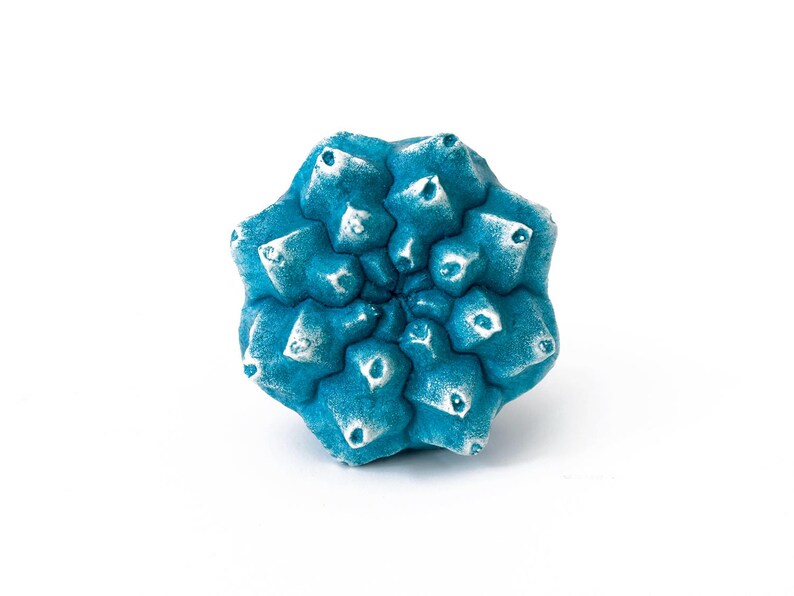 May include: A bright blue, star-shaped object with a textured, multi-faceted surface. The points of the star feature white, weathered-looking highlights, creating a contrast against the deep blue base colour of the geometric, symmetrical form.
