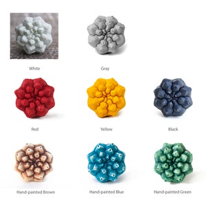 May include: A set of nine ceramic flower-shaped ornaments in various colors, including white, gray, red, yellow, black, brown, blue, and green. The ornaments are all the same shape and size, and they are arranged in a grid pattern.