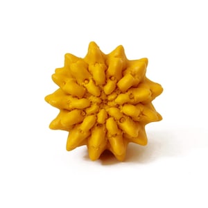 May include: A bright yellow, spherical object with a textured, multi-pointed surface resembling a stylized sun or a geometric flower. The form features numerous protruding, tapered segments radiating from a central point, creating a dense, uniform pattern across the entire exterior of the round item.