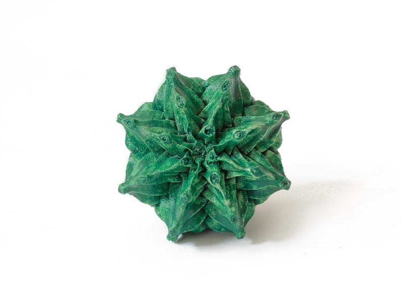 May include: A geometric, star-shaped object in a deep forest green color. The item features a complex, multi-layered structure with numerous pointed, triangular protrusions radiating from the center, creating a dense, textured, and symmetrical form.