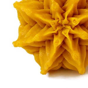 May include: A close-up of a yellow star-shaped cake decoration. The cake decoration is made of a smooth, creamy frosting and has a slightly textured surface.