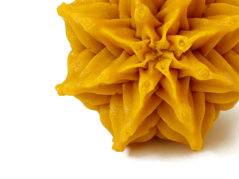 May include: A close-up of a yellow star-shaped cake decoration. The cake decoration is made of a smooth, creamy frosting and has a slightly textured surface.