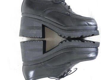 May include: A pair of black platform shoes with a lace-up front. The shoes have a thick platform sole and a chunky heel.