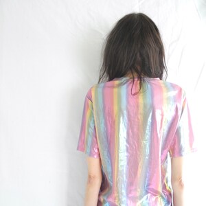 May include: A short-sleeved iridescent shirt with vertical stripes in shades of pink, blue, and green.