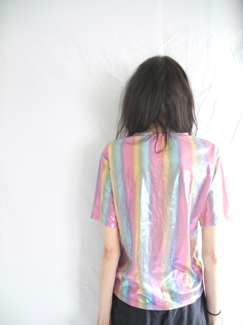 May include: A short-sleeved iridescent shirt with vertical stripes in shades of pink, blue, and green.